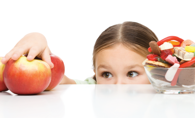 little girl picking between apples and candy