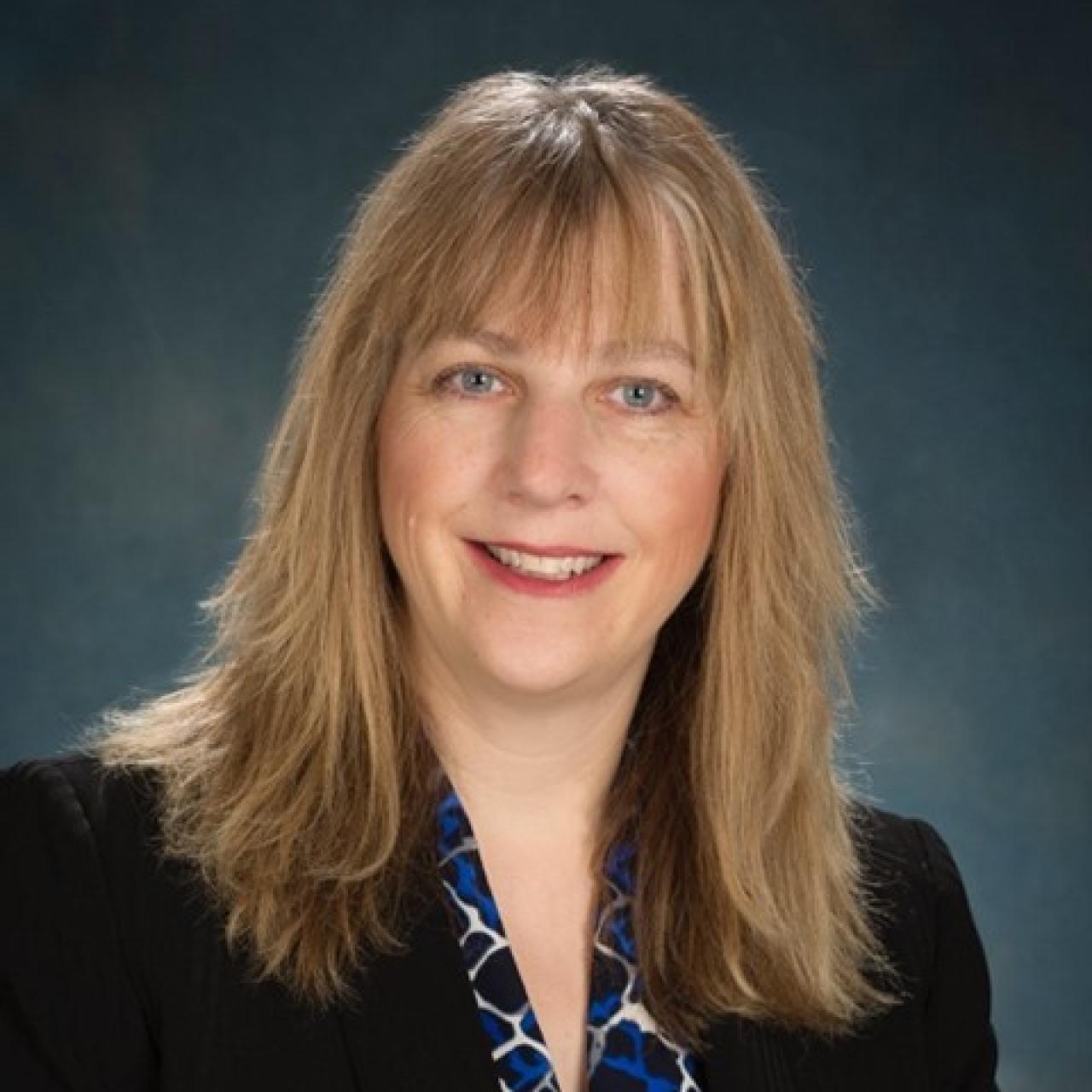 Caucasian female with light colored hair and dark jacket