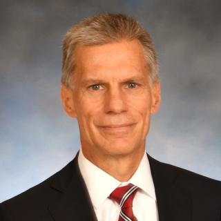 Caucasian male with red striped tie and dark jacket