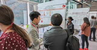young man shares scientific poster with conference attendee