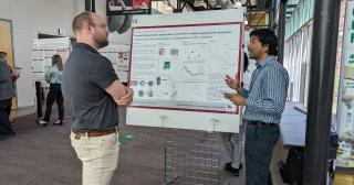 two men talk about a scientific poster together