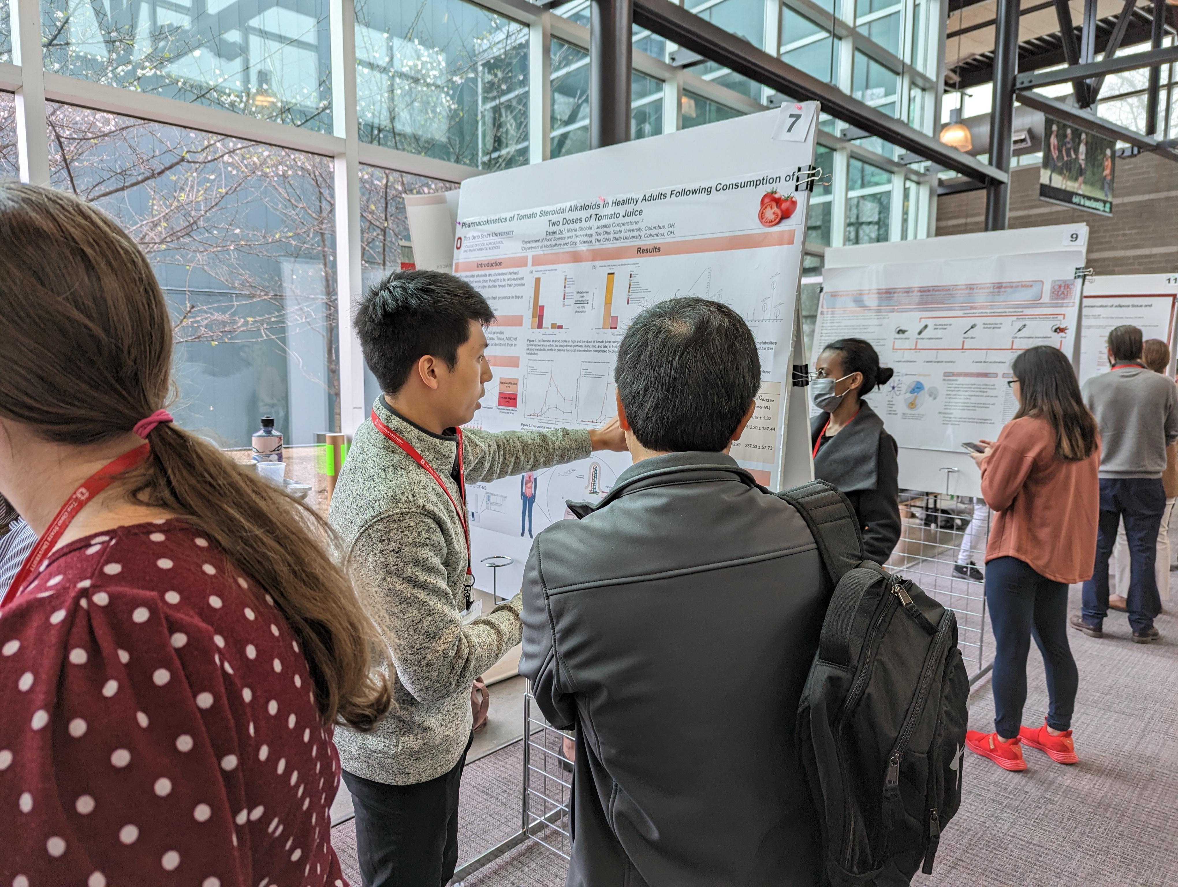 young man shares scientific poster with conference attendee