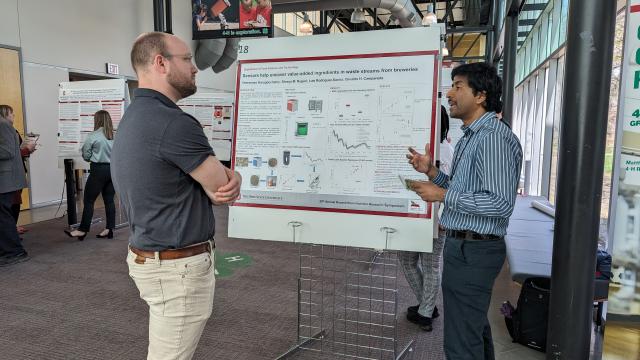 two men talk about a scientific poster together